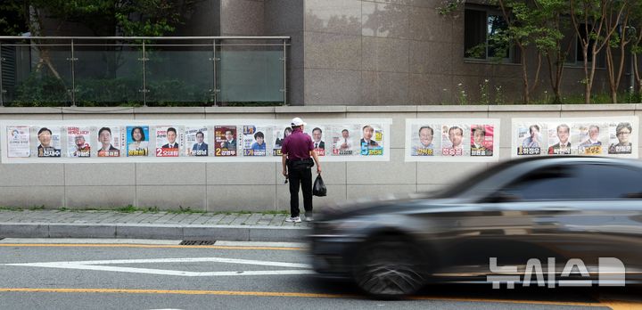 긴 선거벽보 살펴보는 부산 시민