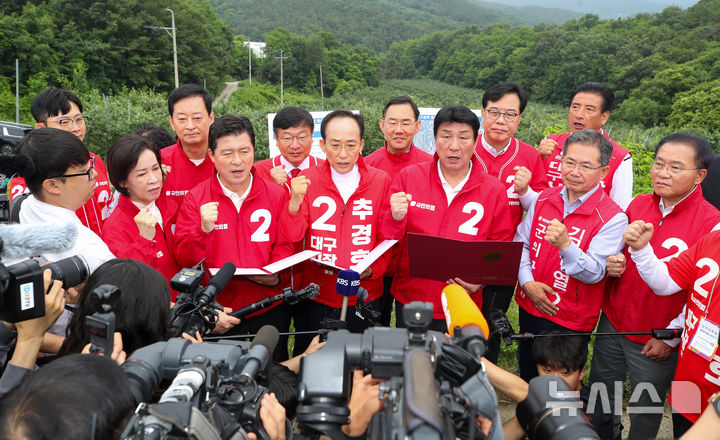 [대구=뉴시스] 이무열 기자 = 국민의힘 추경호(가운데) 대구시장 후보가 28일 오전 대구 군위군 소보면 내의리 대구경북통합신공항 건설 예정지를 찾아 신공항특별법 개정 당론 채택 결의문을 낭독하고 있다. 2026.05.28. lmy@newsis.com
