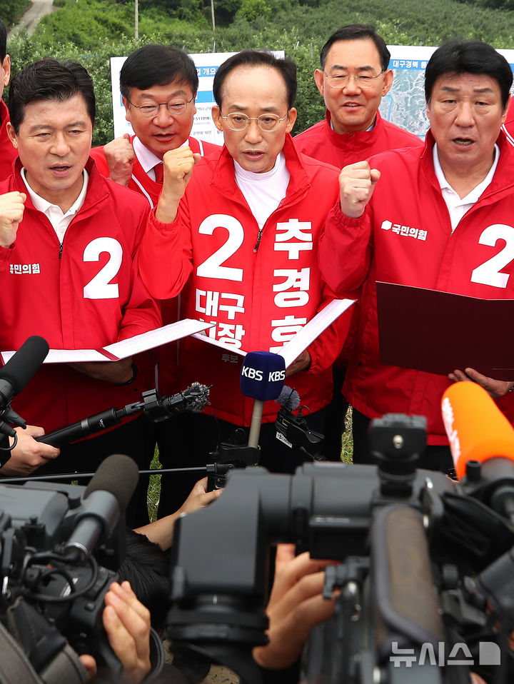 [대구=뉴시스] 이무열 기자 = 추경호(가운데) 국민의힘 대구시장 후보가 28일 오전 대구 군위군 소보면 내의리 대구경북통합신공항 건설 예정지를 찾아 신공항특별법 개정 당론 채택 결의문을 낭독하고 있다. 2026.05.28. lmy@newsis.com