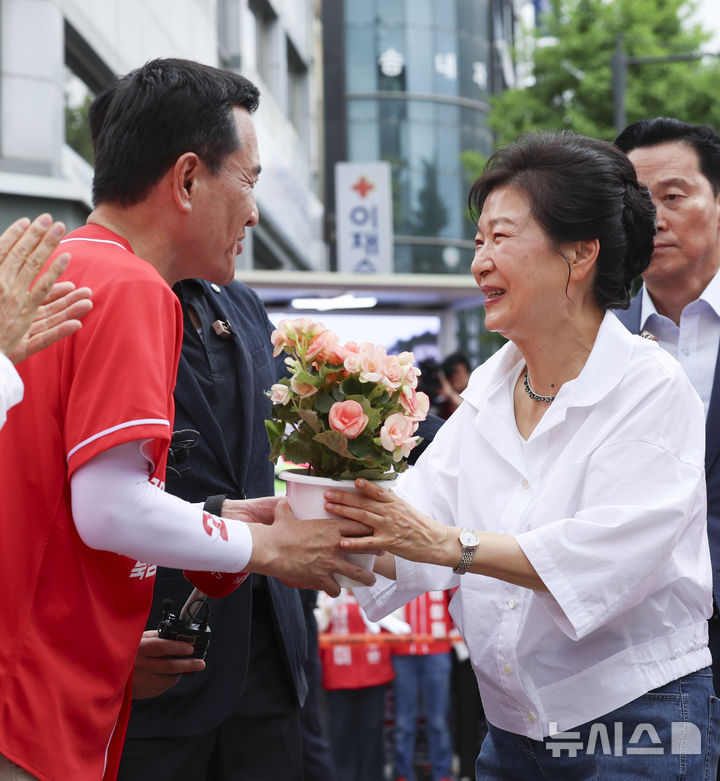 [원주=뉴시스] 김근수 기자 = 박근혜 전 대통령이 28일 오전 강원 원주 중앙시장에서 열린 김진태 국민의힘 강원도지사 후보 지지 현장 방문에서 김 후보에게 꽃 화분을 받고 있다. 2026.05.28. ks@newsis.com