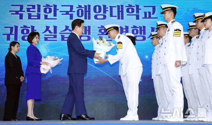 [부산=뉴시스] 고범준 기자 = 이재명 대통령이 27일 부산 영도구에서 열린 제31회 바다의 날 기념식에서 해양대 실습생 귀항 보고를 받으며 꽃다발을 전달하고 있다. 2026.05.27. bjko@newsis.com