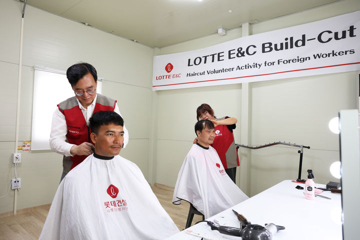[서울=뉴시스] 오일근 롯데건설 대표가 세종시 ‘들목교 외곽순환도로’ 건설현장에서 외국인 근로자들에게 미용 가운을 둘러주고 있다. (사진=롯데건설 제공) 2026.05.31 photo@newsis.com *재판매 및 DB 금지