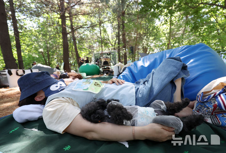 [서울=뉴시스] 조성우 기자 = 31일 서울 성동구 서울숲에서 열린 유한킴벌리 제1회 '우리강산 푸르게 푸르게 숲속 개꿀잠대회'에서 참가자가 반려견과 함께 잠을 자고 있다. 2026.05.31. xconfind@newsis.com