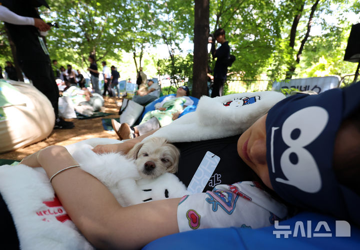 [서울=뉴시스] 조성우 기자 = 31일 서울 성동구 서울숲에서 열린 유한킴벌리 제1회 '우리강산 푸르게 푸르게 숲속 개꿀잠대회'에서 참가자가 반려견과 함께 잠을 자고 있다. 2026.05.31. xconfind@newsis.com