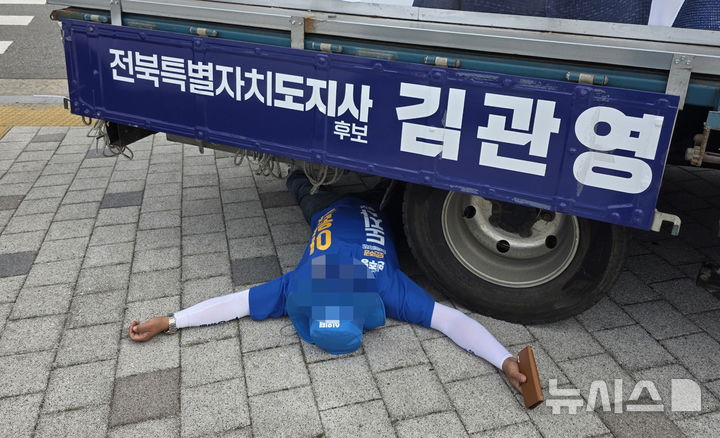 [전주=뉴시스] 김얼 기자 = 제9회 전국동시지방선거를 앞둔 1일 전북 전주시 완산구의 한 네리거에서 더불어민주당 이원택 전북특별자치도지사 후보의 선거운동원이 무소속 김관영 전북특별자치도지사 후보의 유세차량 아래 들어가 누워 있다. (사진=독자 제공) 2026.06.01. pmkeul@newsis.com
