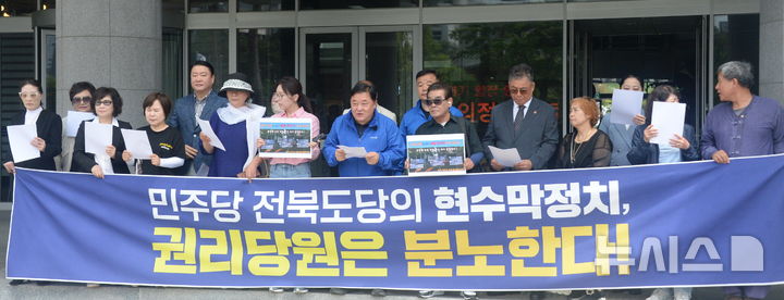 [전주=뉴시스] 김얼 기자 = 더불어민주당 전북특별자치도당 일부 권리당원들이 1일 전북 전주시 전북특별자치도의회 앞에서 '무분별한 현수막 게첨으로 인한 당비손실 초래한 더불어민주당 전북특별자치도당 윤준병 위원장 사퇴 촉구 및 당비 반환 요구' 기자회견을 열고 회견문을 낭독하고 있다. 2026.06.01. pmkeul@newsis.com