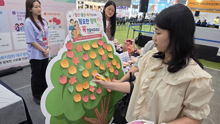 인구보건복지협회 대구경북지회가 마련한 희망나무 메시지판에 시민들이 임신·출산·육아를 위해 필요한 정책이나 바라는 사회 변화에 대한 의견을 작성해 붙이고 있다. *재판매 및 DB 금지
