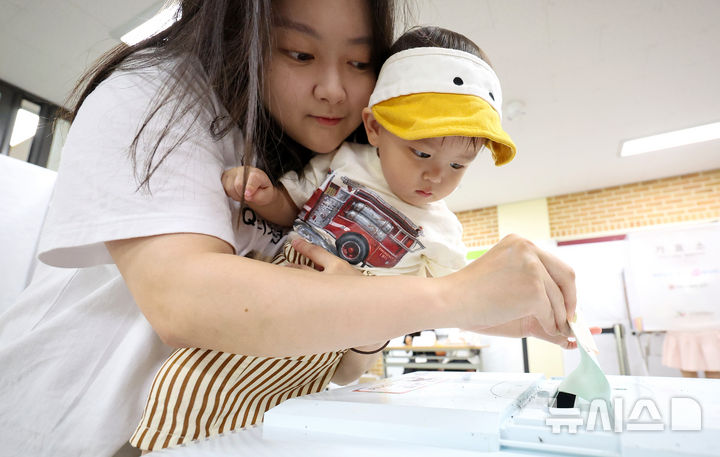 [대구=뉴시스] 이무열 기자 = 제9회 전국동시지방선거일인 3일 오전 대구 달성군 비슬초등학교에 마련된 유가읍 제3투표소에서 아이를 안은 유권자가 투표를 하고 있다. 2026.06.03. lmy@newsis.com