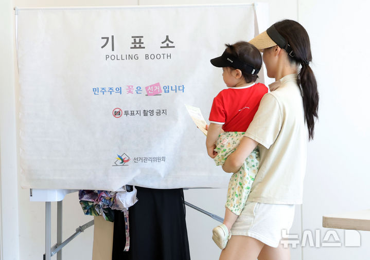 [서울=뉴시스 홍효식 기자 = 한국의 6·3 지방선거 결과에 대해 일본 언론은 여당의 승리로 평가하며, 이재명 대통령이 유권자들로부터 긍정적인 평가를 받고 있다고 진단했다. 다만 서울시장 선거에서 국민의힘 후보가 승리한 데 대해선 '타격'이라는 평가도 나왔다. 사진은 제9회 전국동시지방선거일인 지난 3일 서울 광진구 기아자동차 대공원대리점에 마련된 능동 제3투표소에서 한 유권자가 아이를 안고 기표소로 향하고 있는 모습. 2026.06.04. yesphoto@newsis.com