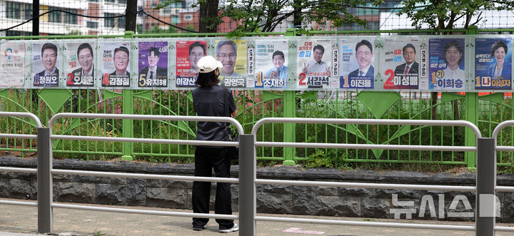 [서울=뉴시스] 홍효식 기자 = 제9회 전국동시지방선거일인 3일 서울 송파구 잠전초등학교 인근에서 한 시민이 선거 벽보를 바라보고 있다. 2026.06.03. yesphoto@newsis.com