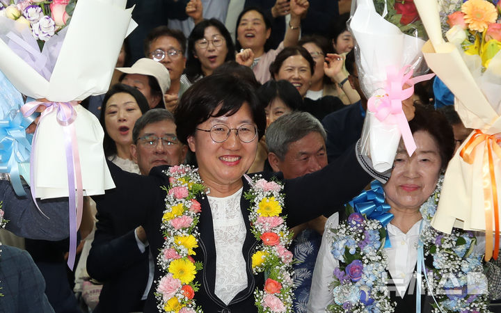[제주=뉴시스] 우장호 기자 = 고의숙 제주도교육감 후보가 3일 제주시 삼도1동에 위치한 선거사무소에서 당선이 확실시 되자 남편 강경식씨와 함께 꽃다발을 목에 걸고 환호하고 있다. 2026.06.03. woo1223@newsis.com