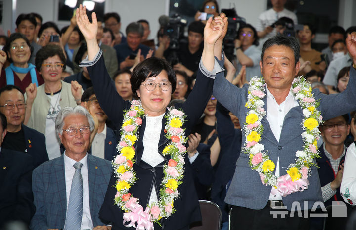 [제주=뉴시스] 우장호 기자 = 고의숙 제주도교육감 후보가 3일 제주시 삼도1동에 위치한 선거사무소에서 당선이 확실시 되자 남편 강경식씨와 함께 꽃다발을 목에 걸고 환호하고 있다. 2026.06.03. woo1223@newsis.com