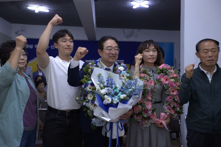 [옥천=뉴시스] 더불어민주당 황규철 충북 옥천군수 후보가 3일 선거사무소에서 가족과 함께 지지자들로부터 꽃다발을 받고 환호하고 있다. (사진=공동취재단) 2026.06.03. photo@newsis.com *재판매 및 DB 금지