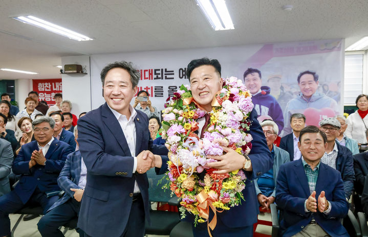 [예산=뉴시스] 최재구 예산군수 당선인이 4일 자신의 선거사무실에서 꽃화환을 목에 걸고 강승규 국회의원과 악수하며 당선 축하 기념 사진을 찍고 있다. (사진=최재구 캠프 제공) 2026.06.04. photo@newsis.com *재판매 및 DB 금지