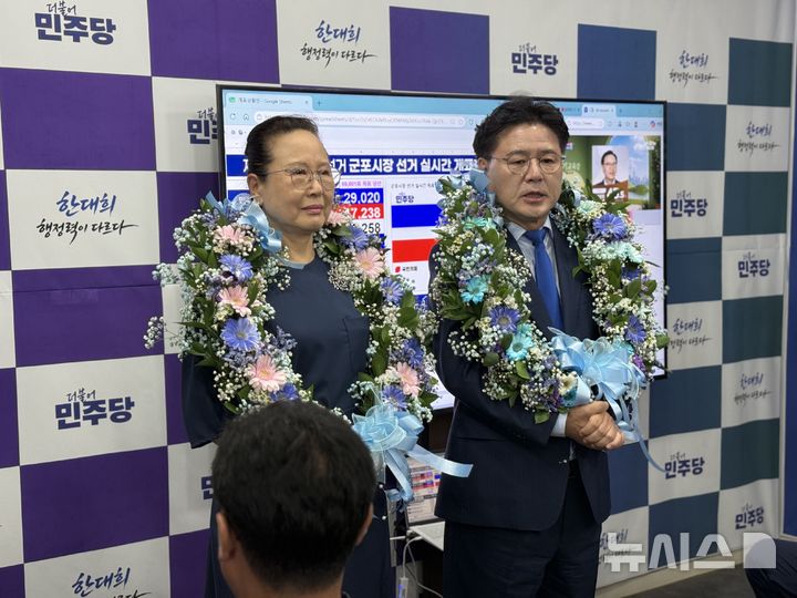 [군포=뉴시스] 한대희 당선인(사진 오른쪽)이 목에 꽃다발을 걸고 지지자들에게 인사하고 있다. (사진=선거사무소 제공).2026.06.04.photo@newsis.com