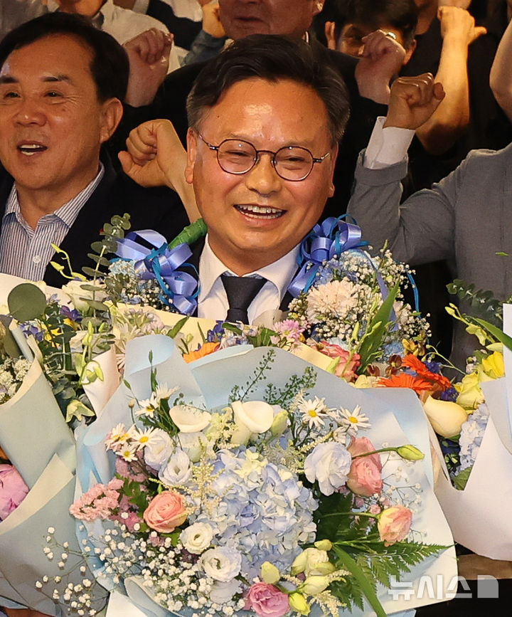 [서귀포=뉴시스] 우장호 기자 = 김성범 더불어민주당 서귀포시 국회의원 보궐선거 후보가 3일 제주 서구포시 서홍동에 위치한 선거사무소에서 당선이 확실시 되자 꽃다발을 들고 환호하고 있다. (사진=제주도사진기자회) 2026.06.04. woo1223@newsis.com