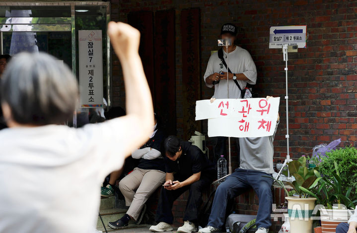 [서울=뉴시스] 홍효식 기자 = 4일 6·3 지방선거 투표용지 부족 사태를 겪은 서울 송파구 잠실7동 제2투표소 앞에서 시민들이 '선거관리위원회 해체, 부정선거, 재선거' 구호를 외치고 있다. 2026.06.04. yesphoto@newsis.com