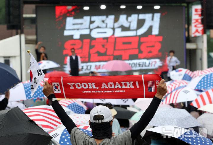 [과천=뉴시스] 조성우 기자 = 4일 경기 과천시 중앙선거관리위원회 과천청사 앞에서 열린 투표용지 부족 사태 관련 항의 집회에서 한 참가자 '윤어게인' 이라고 적힌 손팻말을 펼치고 있다. 2026.06.04. xconfind@newsis.com