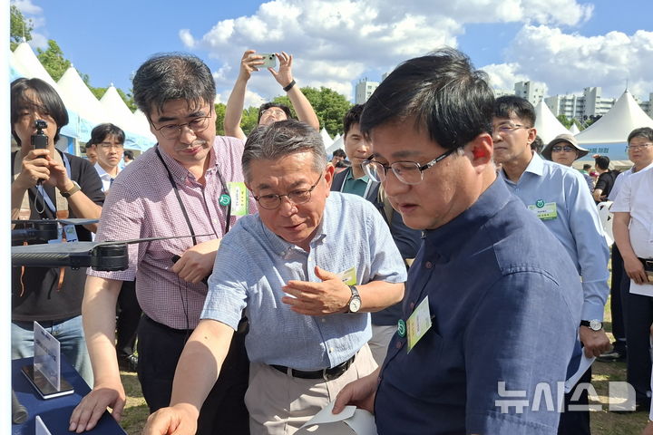 [세종=뉴시스]김준동 남부발전 사장(가운데)이 5일 한강잠원공원 홍보부스에서 김성환 기후부 장관(오른쪽)에게 건물일체형태양광(BIPV) 패널에 대해 설명하고 있다.(사진=남부발전 제공)