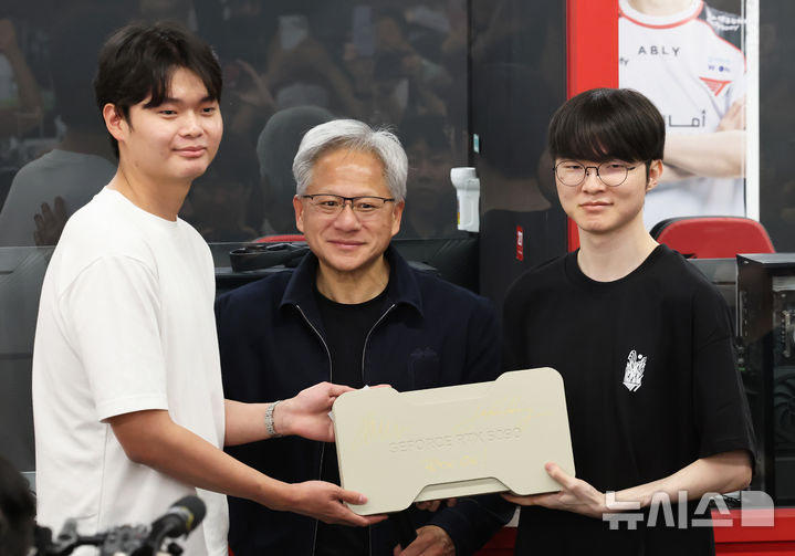 [서울=뉴시스] 조성우 기자 = 젠슨 황(가운데) 엔비디아 최고경영자(CEO)가 5일 서울 마포구 'T1 베이스 캠프'에서 '페이커' 이상혁을 비롯한 e스포츠 구단 T1의 리그 오브 레전드(LoL) 선수단을 만나서 한 팬에게 추첨을 통해 사인이 담긴 엔비디아의 차세대 플래그십 그래픽카드인 ‘지포스 RTX 5090’을 선물하고 있다. (공동취재) 2026.06.05. photo@newsis.com