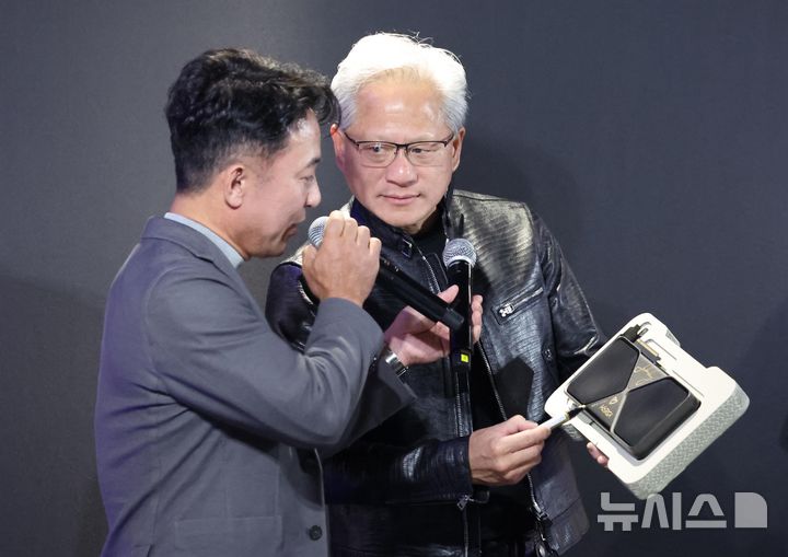 [서울=뉴시스] 권창회 기자 = 젠슨 황 엔비디아 최고경영자가 7일 서울 강남구의 한 PC방에서 열린 AION2 서프라이즈 라이브에 참석, 최신 그래픽카드 '지포스RTX5090'에 사인하고 있다. 왼쪽은 김택진 엔씨소프트 대표이사. (공동취재) 2026.06.07. photo@newsis.com