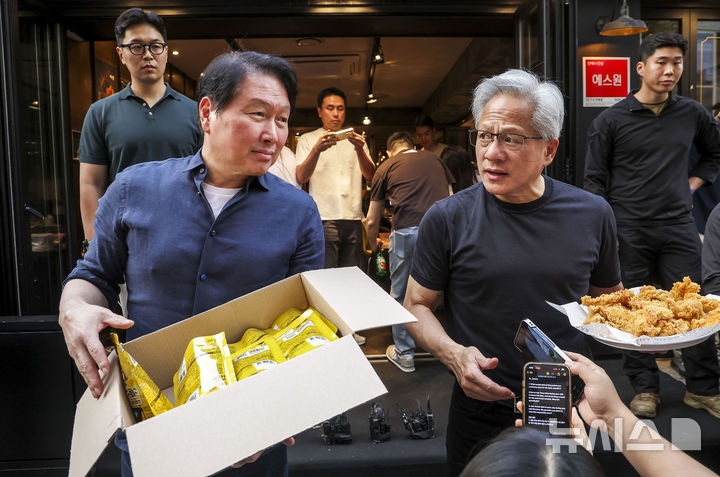 [서울=뉴시스] 정병혁 기자 = 젠슨 황 엔비디아 최고경영자(CEO)와 최태원 SK 회장이 7일 서울 강남구 깐부치킨 삼성점에서 치맥회동 도중 취재진과 시민들에게 치킨과 HBM칩을 나눠주고 있다. 2026.06.07. jhope@newsis.com