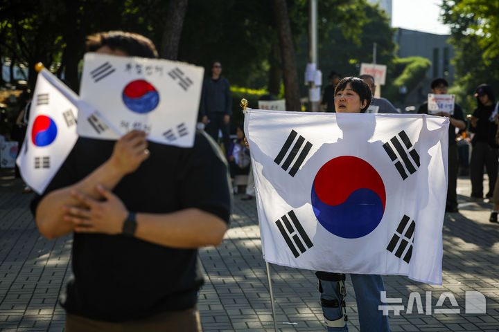 [서울=뉴시스] 정병혁 기자 = 제9회 전국동시지방선거 투표용지 부족 사태에 항의하며 개표소 봉쇄 시위를 이어가는 시민들이 9일 서울 송파구 올림픽공원 핸드볼경기장에 설치된 개표소 앞에서 재선거를 촉구하며 태극기를 흔들고 있다. 2026.06.09. jhope@newsis.com