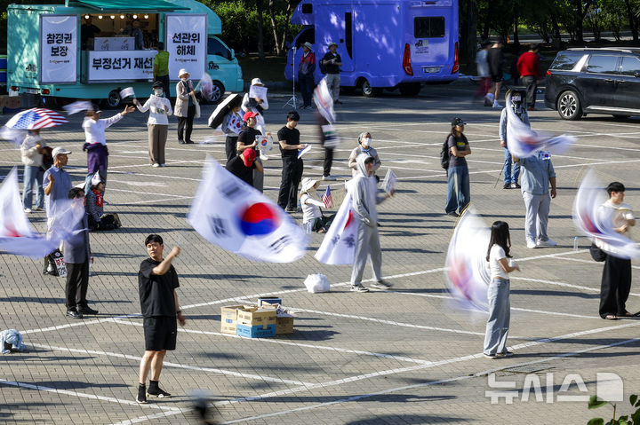 [서울=뉴시스] 정병혁 기자 = 제9회 전국동시지방선거 투표용지 부족 사태에 항의하며 개표소 봉쇄 시위를 이어가는 시민들이 9일 서울 송파구 올림픽공원 핸드볼경기장에 설치된 개표소 앞에서 재선거를 촉구하며 태극기를 흔들고 있다. 2026.06.09. jhope@newsis.com