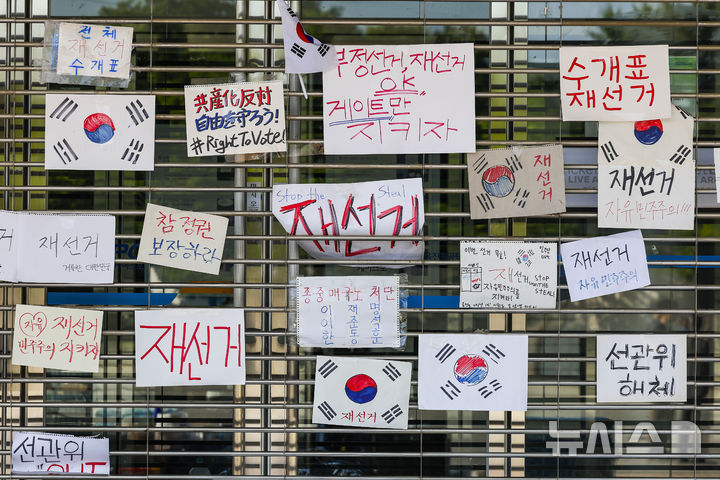 [서울=뉴시스] 정병혁 기자 = 제9회 전국동시지방선거 투표용지 부족 사태에 항의하며 개표소 봉쇄 시위를 이어고 있는 가운데 9일 서울 송파구 올림픽공원 핸드볼경기장에 설치된 개표소 앞에 재선거 촉구 피켓이 붙어 있다. 2026.06.09. jhope@newsis.com