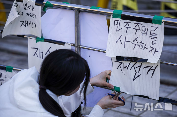 [서울=뉴시스] 정병혁 기자 = 제9회 전국동시지방선거 투표용지 부족 사태에 항의하며 개표소 봉쇄 시위를 이어가는 시민들이 9일 서울 송파구 올림픽공원 핸드볼경기장에 설치된 개표소에 피켓을 붙이고 있다. 2026.06.09. jhope@newsis.com