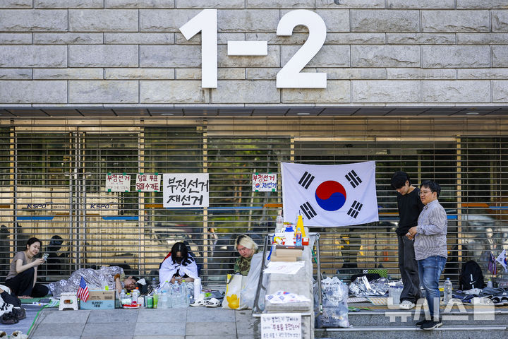 [서울=뉴시스] 정병혁 기자 = 제9회 전국동시지방선거 투표용지 부족 사태에 항의하며 개표소 봉쇄 시위를 이어가는 시민들이 9일 서울 송파구 올림픽공원 핸드볼경기장에 설치된 개표소 앞에 앉아 있다. 2026.06.09. jhope@newsis.com