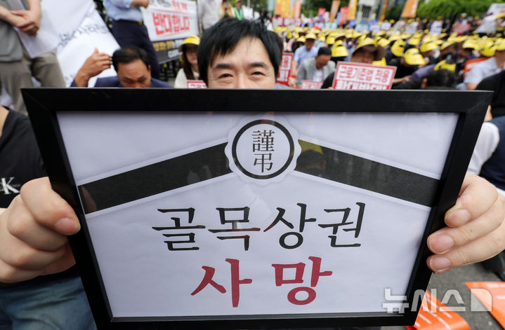 [서울=뉴시스] 홍효식 기자 = 지난 9일 오후 서울 영등포구 국회 인근에서 열린 생존권 사수와 고용 정책 대전환 촉구 범 소상공인 결의대회에서 소상공인연합회 등 참가자들이 골목상권 사망 피켓을 들고 있다. 2026.06.21. yesphoto@newsis.com