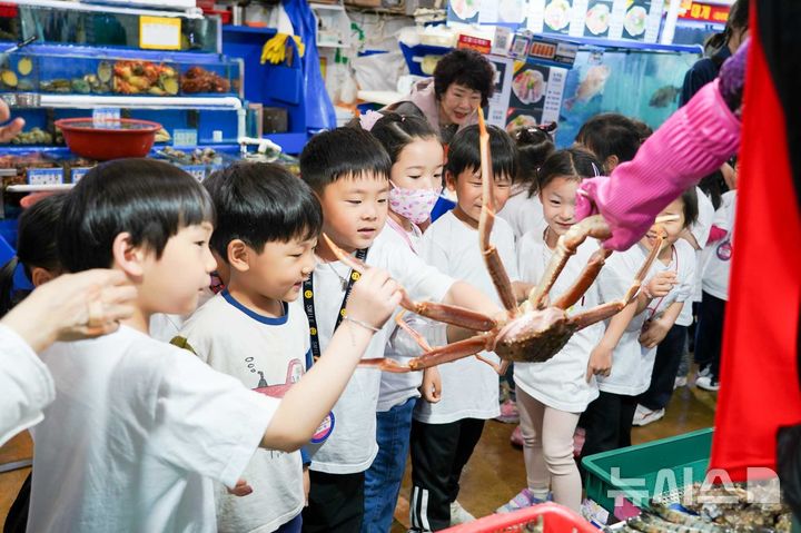 [서울=뉴시스] '어린이 일일 해양교육 현장체험'에 참여한 어린이들이 수산물을 직접 만져보고 있다.