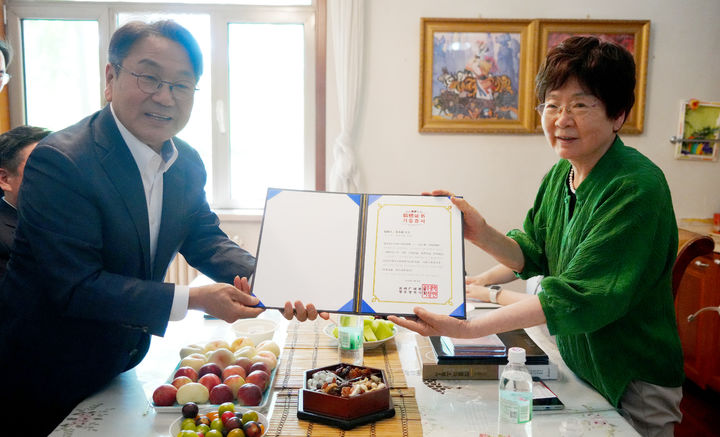 [광주=뉴시스] 강기정 광주시장과 정율성 선생의 딸 정소제씨가 '3·1행진곡' 악보 복제본과 '정율성 연보' 책자 기증서를 들어 보이고 있다. (사진=공동취재단). photo@newsis.com *재판매 및 DB 금지