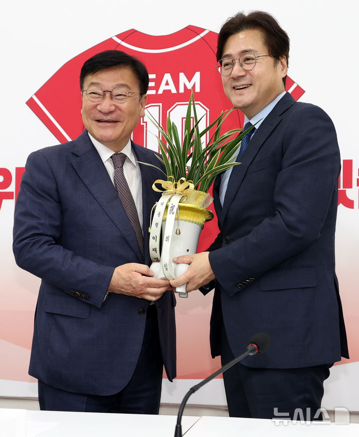 [서울=뉴시스] 최진석 기자 = 정점식(왼쪽) 국민의힘 신임 원내대표가 11일 오후 여의도 국회에서 홍익표 대통령비서실 정무수석으로부터 이재명 대통령이 보낸 축하난을 받고 있다. 2026.06.11. myjs@newsis.com