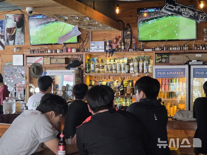 [전주=뉴시스] 강경호 기자 = 대한민국 축구 국가대표팀의 2026 국제축구연맹(FIFA) 북중미 월드컵 조별리그 첫 경기가 열린 12일(한국시간) 전북 전주시 덕진구 전북대학교 대학로의 한 펍에서 대표팀을 응원하기 위해 가게를 찾은 손님들이 경기를 시청하고 있다. 2026.06.12. lukekang@newsis.com