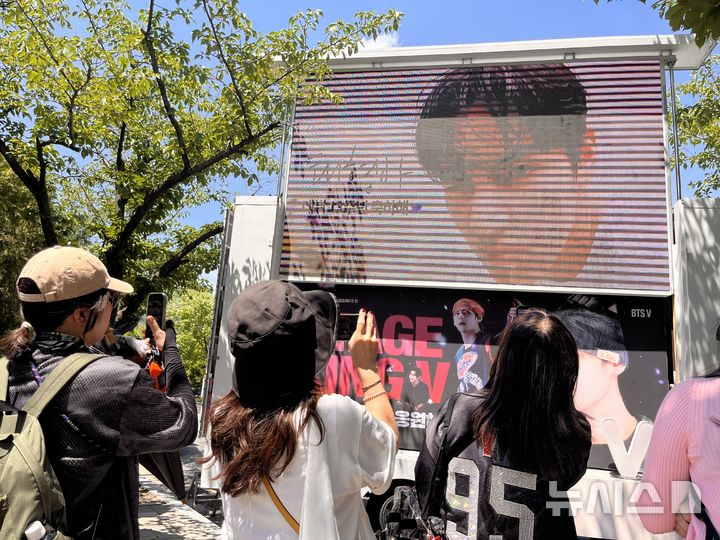 [부산=뉴시스] 진민현 기자 = 12일 오후 부산 연제구 부산아시아드주경기장 인근에 설치된 BTS 멤버 뷔(V) 래핑트럭 앞에서 팬들이 기념사진을 촬영하고 있다. BTS 월드투어 '아리랑 인 부산' 공연을 앞두고 공연장 일대는 팬들로 북적였다. 2026.06.12. truth@newsis.com