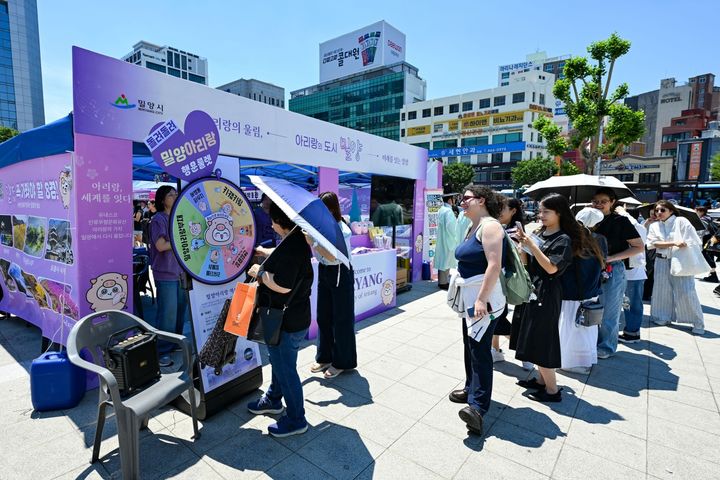 [밀양=뉴시스] 부산역 광장 밀양 브랜드로드쇼 홍보부스에서 관광객들이 아리랑 행운의 룰렛 이벤트에 참여하고 있다. (사진=밀양시 제공) 2026.06.13. photo@newsis.com *재판매 및 DB 금지
