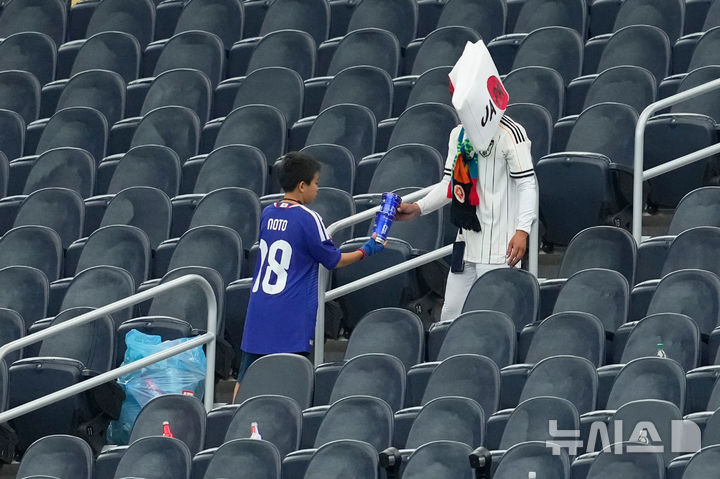 [텍사스=AP/뉴시스] 14일(현지 시간) 미국 텍사스주 알링턴 댈러스 스타디움에서 열린 2026 북중미 월드컵 조별리그 F조 1차전 일본과 네덜란드 경기 종료 후 일본 축구 팬들이 쓰레기를 치우고 있다. 2026.06.15.