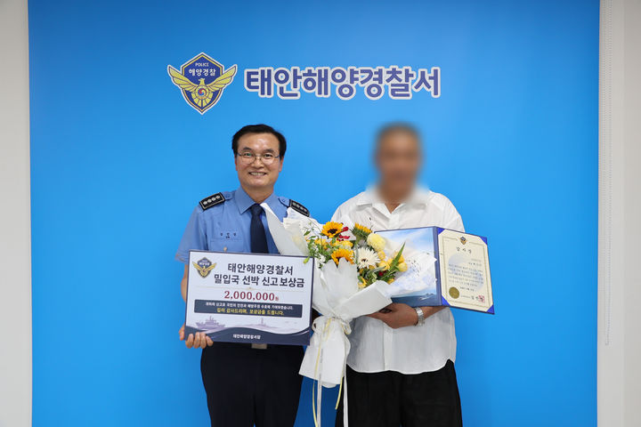 [태안=뉴시스] 김진영(왼쪽) 태안해양경찰서장이 15일 본서에서 중국인 밀입국자 검거에 기여한 60대 선장에게 포상금을 지급한 뒤 함께 기념 사진을 찍고 있다. (사진=태안해양경찰서 제공) 2026.06.15. photo@newsis.com *재판매 및 DB 금지