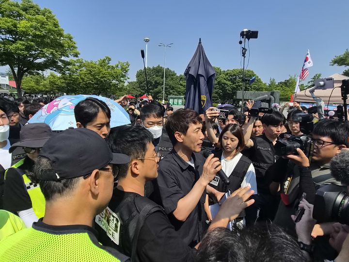 [서울=뉴시스]조수원 기자=6·3 지방선거 투표용지 부족 사태를 규탄하는 개표소 봉쇄 시위가 12일째 이어지는 가운데 16일 체육단체 직원들의 서울 송파구 올림픽공원 핸드볼경기장 진입이 무산됐다. 사진은 경찰 관계자가 시위대를 향해 경고방송하는 모습.2026.06.16 tide1@newsis.com *재판매 및 DB 금지