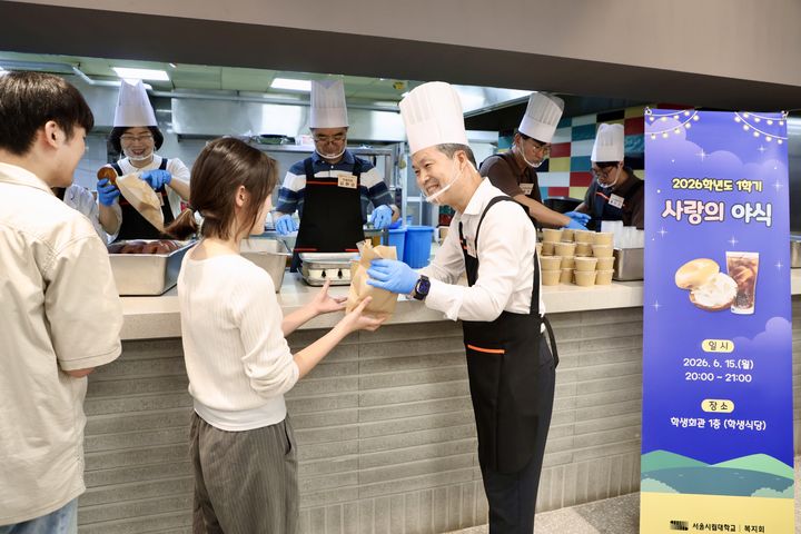 [서울=뉴시스] 15일 서울시립대 학생회관 식당에서 원용걸 총장이 '2026학년도 1학기 기말고사 사랑의 야식' 간식을 학생에게 전달하고 있다. (사진=서울시립대 제공) 2026.06.17. photo@newsis.com *재판매 및 DB 금지
