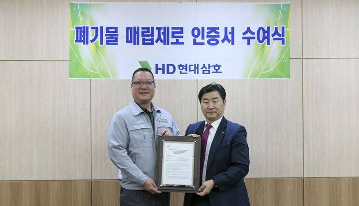[영암=뉴시스] HD현대삼호 지원관에서 최근 열린 '폐기물 매립 제로 인증서 수여식'에서 회사 최고안전책임자 이승훈 상무(왼쪽)와 로이드인증원 이일형 대표이사가 기념촬영을 하고 있다. (사진=HD현대삼호 제공) 2026.06.17. photo@newsis.com *재판매 및 DB 금지