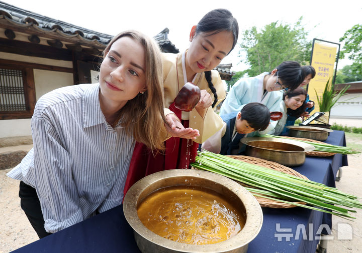[서울=뉴시스] 김진아 기자 = 단오(6월 19일)를 앞두고 17일 서울 종로구 국립민속박물관 오촌댁 앞마당에서 열린 '단오 세시' 행사에서 외국인과 어린이가 창포물에 머리감기 체험을 하고 있다. 22026.06.17. bluesoda@newsis.com