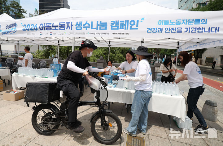 [서울=뉴시스] 김선웅 기자 = 17일 서울 청계천 장통교에서 고용노동부가 주최한 2026 이동노동자 생수나눔 캠페인에서 관계자가 이동노동자에게 생수, 냉감용품 세트를 전달하고 있다. 2026.06.17. mangusta@newsis.com