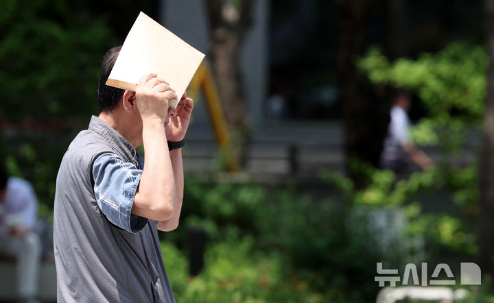 [서울=뉴시스] 이영환 기자 = 서울의 낮기온이 30도를 넘어서며 더위가 이어지고 있는 17일 서울 종로구 광화문광장 한 시민이 햇빛을 가리며 이동하고 있다. 2026.06.17. 20hwan@newsis.com