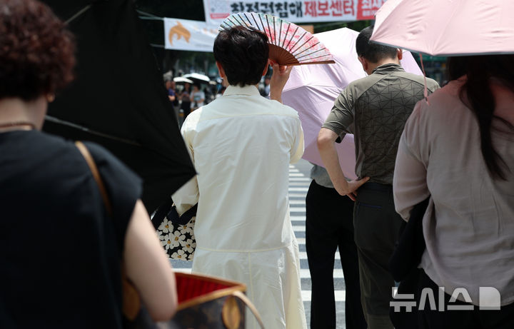 [서울=뉴시스] 이영환 기자 = 서울의 낮기온이 30도를 넘어서며 더위가 이어지고 있는 17일 서울 종로구 광화문광장에서 시민이 부채로 햇빛을 가리고 있다. 2026.06.17. 20hwan@newsis.com