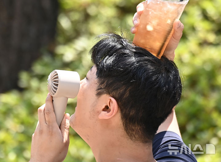 [수원=뉴시스] 김종택 기자 = 목요일인 18일은 전국 대부분 지역에서 낮 최고 기온이 30도 안팎으로 오르며 덥겠다. 오후에는 전국 곳곳에 소나기가 내리겠다. 사진은 연일 무더위가 이어지고 있는 17일 경기 수원시 팔달구 인계동에서 한 시민이 손선풍기와 얼음이 들어있는 음료컵을 머리에 올리며 더위를 식히고 있는 모습. 2026.06.17. jtk@newsis.com