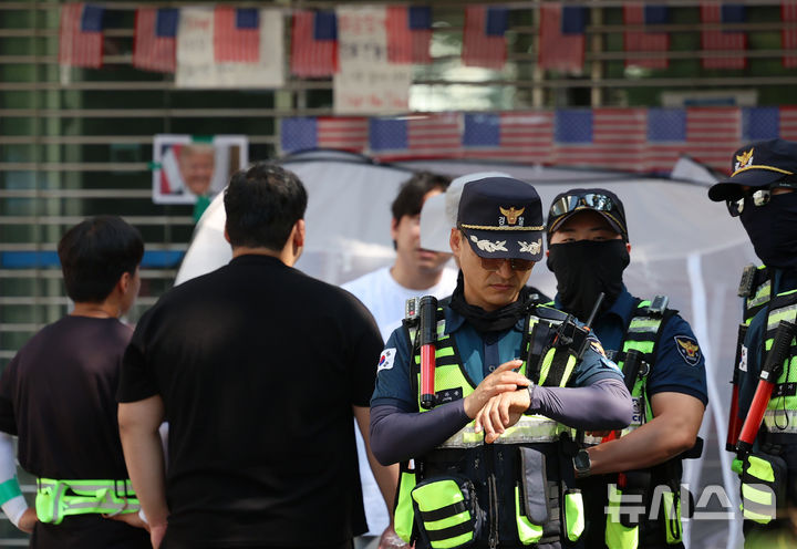 [서울=뉴시스] 조성우 기자 = 18일 오전 6·3 지방선거 투표용지 부족 사태를 규탄하는 시위가 14일째 열리고 있는 서울 송파구 올림픽공원 핸드볼경기장 앞에서 경찰이 경계 근무를 서고 있다. 2026.06.18. xconfind@newsis.com