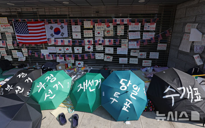 [서울=뉴시스] 조성우 기자 = 18일 오전 6·3 지방선거 투표용지 부족 사태를 규탄하는 시위가 14일째 열리고 있는 서울 송파구 올림픽공원 핸드볼경기장 앞에서 시위 참가자들이 출입문을 지키고 있다. 2026.06.18. xconfind@newsis.com